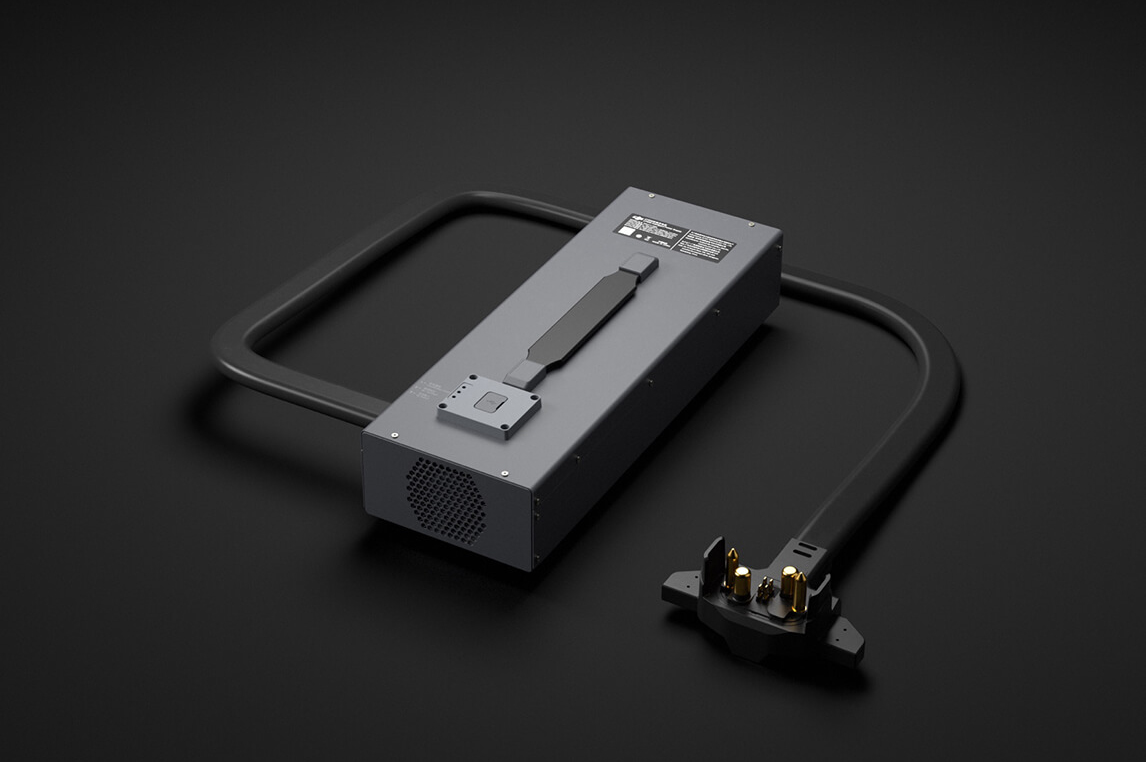 Grey DJI charger with a carry handle and a heavy mains lead with plug, shown on a dark background